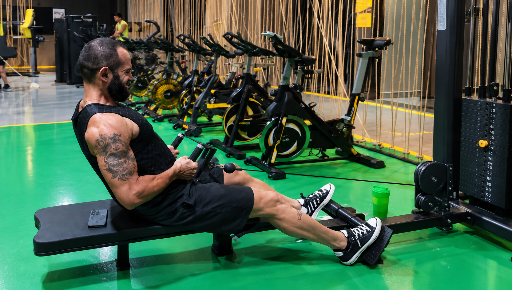 Aluna treinando com barra na área de musculação